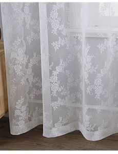 Vue détaillée des motifs de dentelle rose sur un voilage blanc transparent pour salon