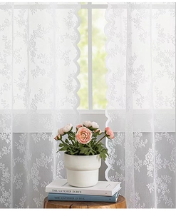 Détail du rideau en dentelle blanche avec broderie florale et bordure festonnée