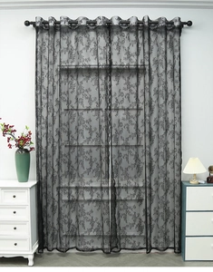 Détail d'un rideau en dentelle noire avec broderie florale et œillets en métal