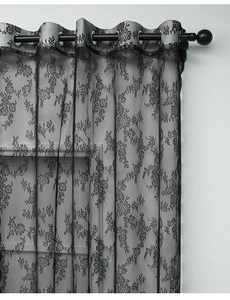 Détail d'un rideau vintage en dentelle noire avec motifs floraux et œillets métalliques