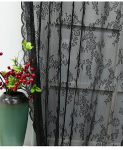 Détail d'un rideau en dentelle noire avec motifs de roses et bordure festonnée