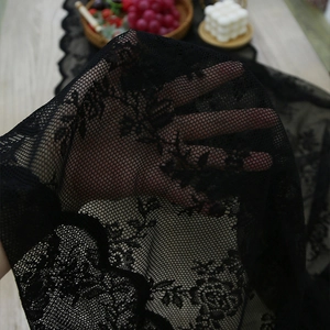 Vintage black lace table runner with floral embroidery on a rustic wooden table