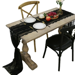 Elegant black lace table runner with hollow floral pattern on a wooden dining table