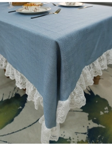 Close-up of greyish-blue tablecloth with detailed white lace border and fabric texture