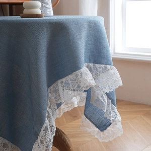 Tovaglia in lino grigio-blu con pizzo bianco su un tavolo tondo in legno stile nordico