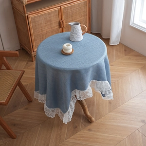 Blue linen table cloth with white lace edge on a wooden table in a rustic room