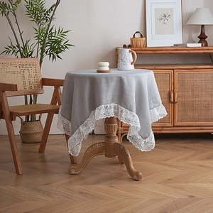 Close-up of grey tablecloth with intricate white lace border on round dining table