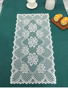 Detailed close-up of white vintage lace table runner with floral embroidery and mesh texture