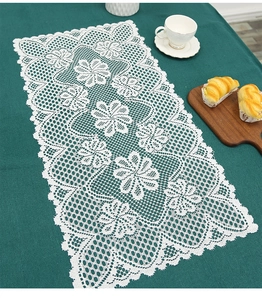 Detail of white lace table runner with intricate floral patterns and scalloped edges
