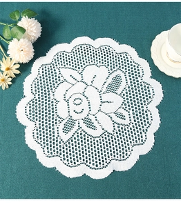 Macro detail of white crochet lace coaster featuring an elegant rose flower pattern