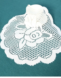 Macro view of a white circular lace coaster with detailed crochet floral hollow patterns