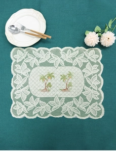 Close-up of white lace placemat with palm tree embroidery and scalloped edges