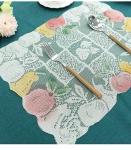 Detail view of round floral lace placemat with fruit patterns and scalloped edges
