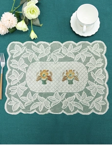 Macro shot of white rectangle lace placemat with orange floral embroidery on a dark green table