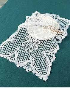 Macro shot of white cotton lace placemat with floral embroidery and honeycomb hollow pattern