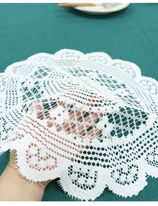 Close-up of white handmade lace coaster with intricate floral hollow patterns