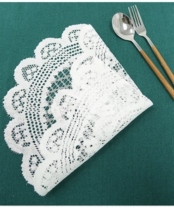 Detailed close-up of white lace table mat featuring intricate hollowed-out floral embroidery