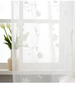 Detailed close-up of white floral embroidery on translucent voile window curtain fabric