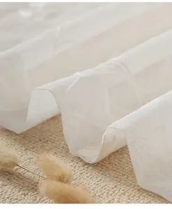 Macro shot of white sheer curtain fabric with delicate floral embroidery and mesh texture