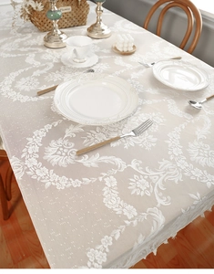Detailed close-up of cream lace tablecloth with floral jacquard and tassel edges