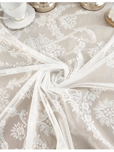 Close-up of white lace tablecloth featuring delicate floral embroidery and mesh texture