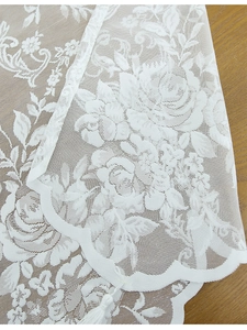 Detailed macro view of white rose lace fabric with elegant scallop edges and fringe trim