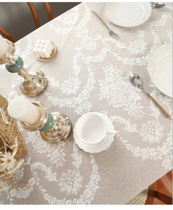 Macro view of beige lace tablecloth featuring elegant rose jacquard patterns and tassel edges