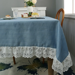Blue linen tablecloth with wide white lace edges shown in a cozy dining setting