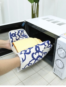 Close-up of thick cotton oven mitts with blue geometric pattern taking bread out of microwave