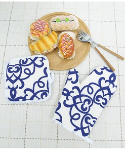 Detail of blue floral oven mitt and pot holder on a rustic kitchen table setting