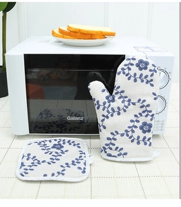 Floral oven mitt and pot holder set on a dining table near a microwave oven