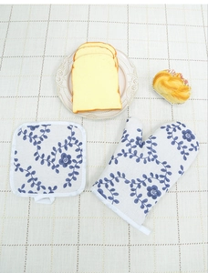 Detail of floral oven mitt and square pot holder on a rustic plaid tablecloth