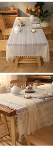 Close-up of beige lace tablecloth featuring geometric hollow patterns and fringe tassels