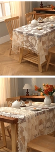Detailed view of beige lace tablecloth with floral patterns and soft tassel edge decor