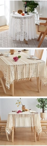 Detail of white hollow lace round tablecloth and beige tassel geometric dining covers