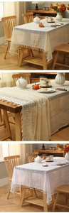 Close-up of cream lace tablecloth featuring floral hollow patterns and tassel fringe edge