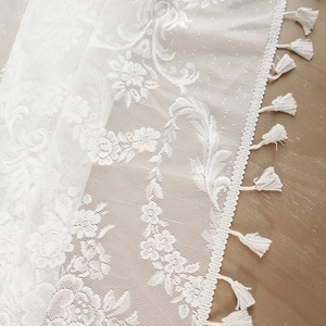 White French lace tablecloth with vintage rose patterns and tassel fringe on wood