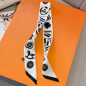 Detail of a black and white floral twilly scarf with camellia print on an orange gift box