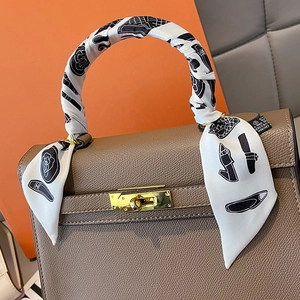 Close-up of printed silk scarf wrapped around a brown leather handbag handle