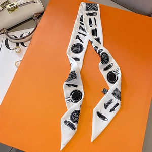 French style narrow silk scarf with fashion motifs on orange box next to a white bag