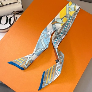 Elegant chain print twilly silk scarf draped on an orange gift box with equestrian motifs