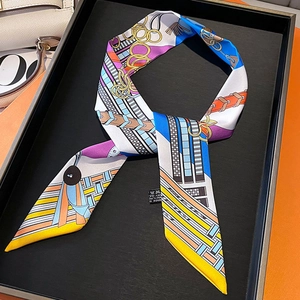 Close-up of chain print twilly silk scarf with equestrian patterns in luxury orange box