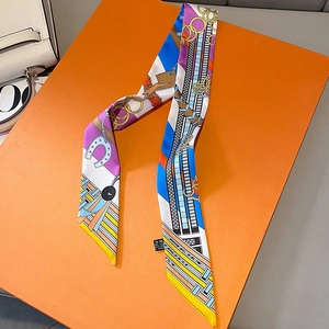 Close-up of luxury twilly silk scarf with equestrian chain print on iconic orange box