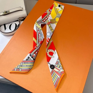 Close-up of equestrian chain print silk scarf draped over a luxury orange gift box