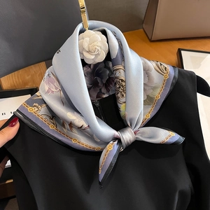 Sky blue silk scarf with floral and chain patterns styled on a black outfit
