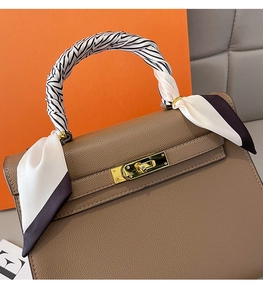 Detailed close-up of tan textured leather bag with zebra pattern silk scarf handle wrap