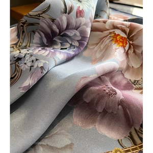 Macro shot of floral silk square scarf with purple peonies on grey-blue satin fabric