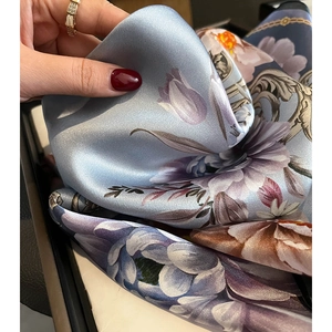 Close-up of elegant floral print silk scarf showing smooth texture and rolled edges