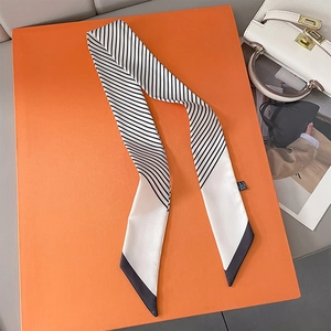 Classic black and white striped silk scarf with pointed ends on a vibrant orange background