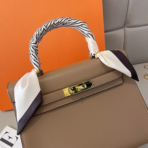 Brown lychee leather handbag with decorative black and white silk scarf on the top handle